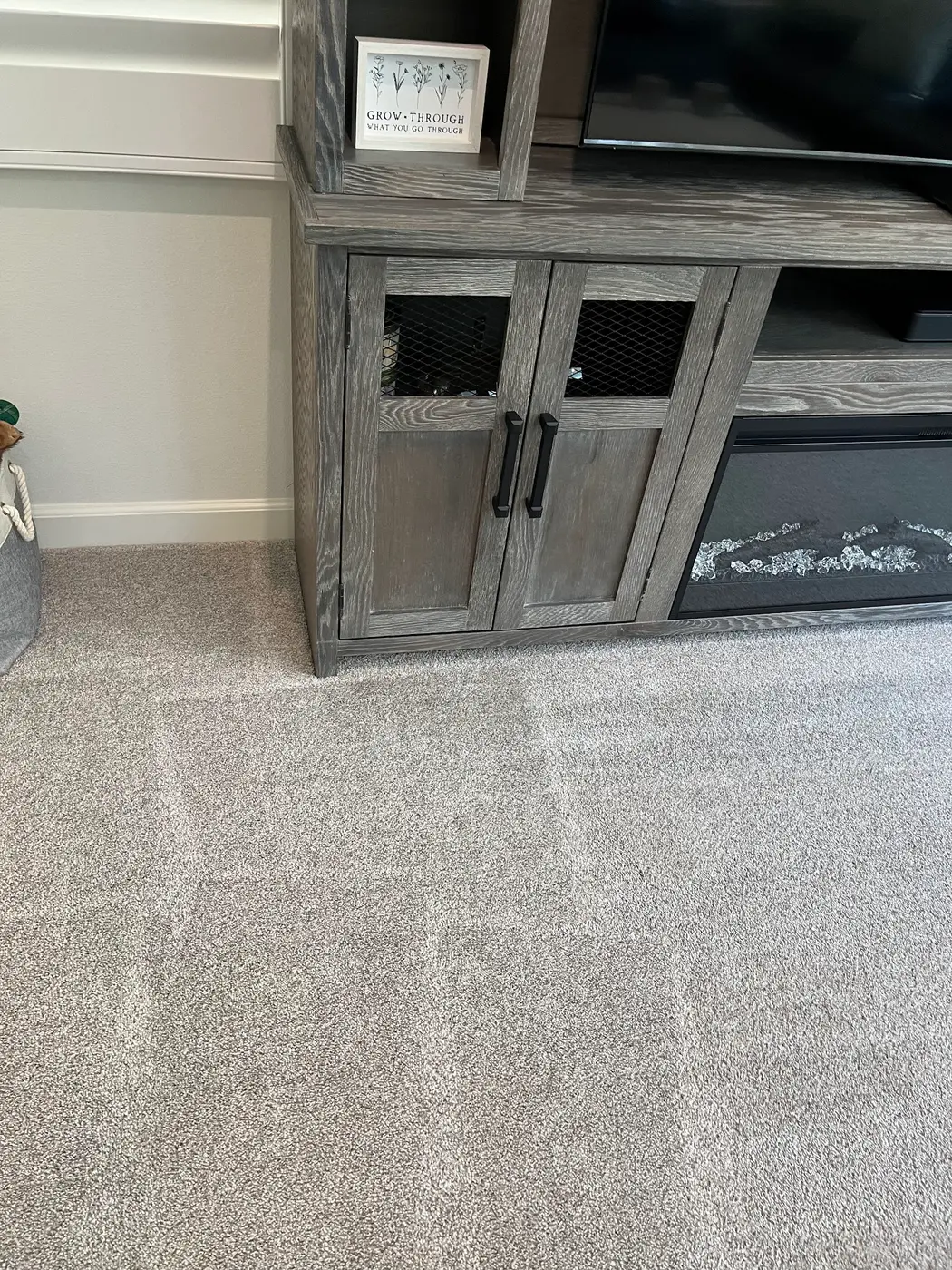 Carpet spot by a cabinet beside the cleaned carpet after cleaning