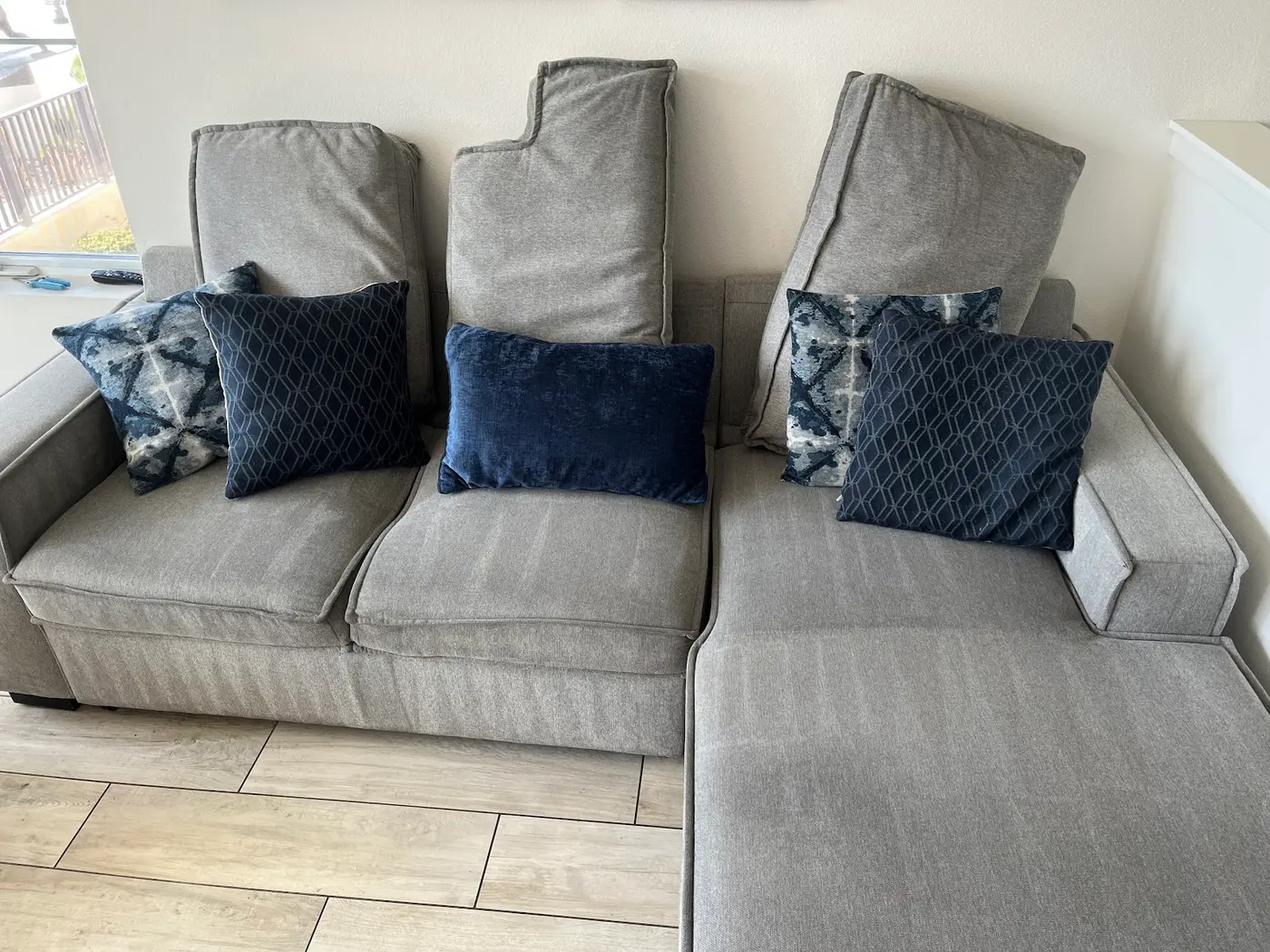 Couch cushions, soiled seats beside the cleaned couch after cleaning