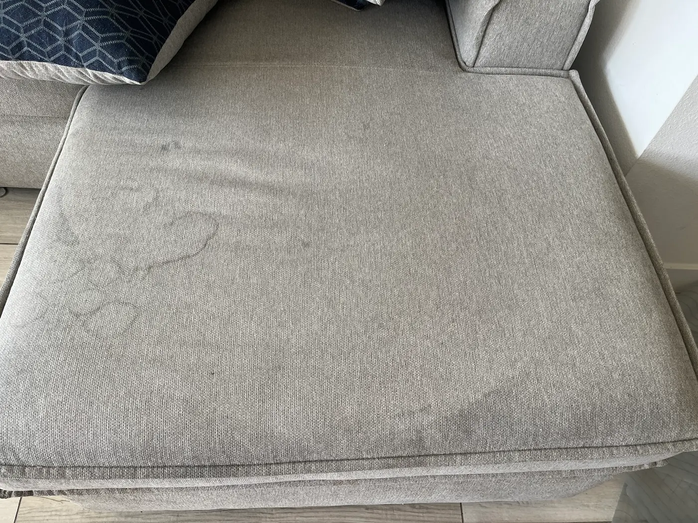 Couch cushions, soiled seats beside the cleaned couch before cleaning