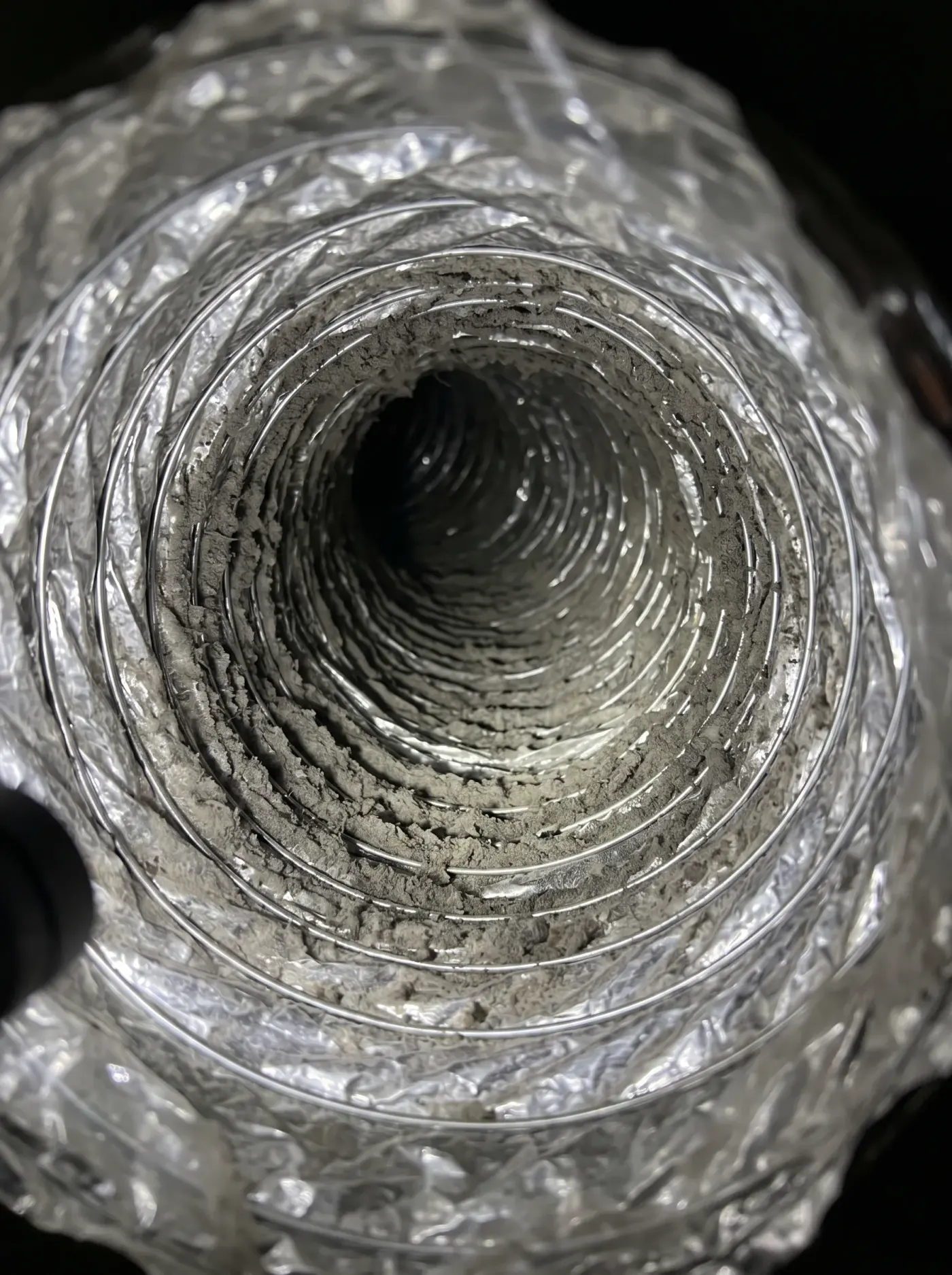 Flexible duct, debris on the ribs beside the cleared liner before cleaning