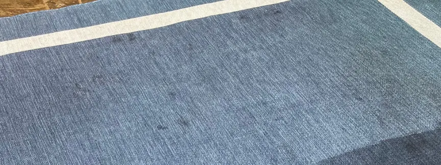 Blue area rug, soiled field beside a lighter cleaned pass after cleaning