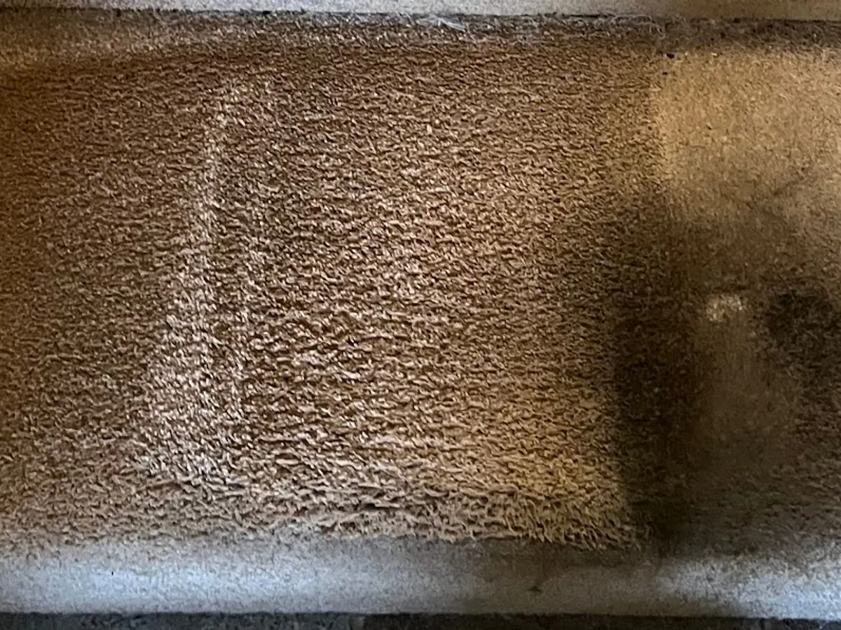 Stair landing, the soiled bottom step beside the cleaned landing before cleaning