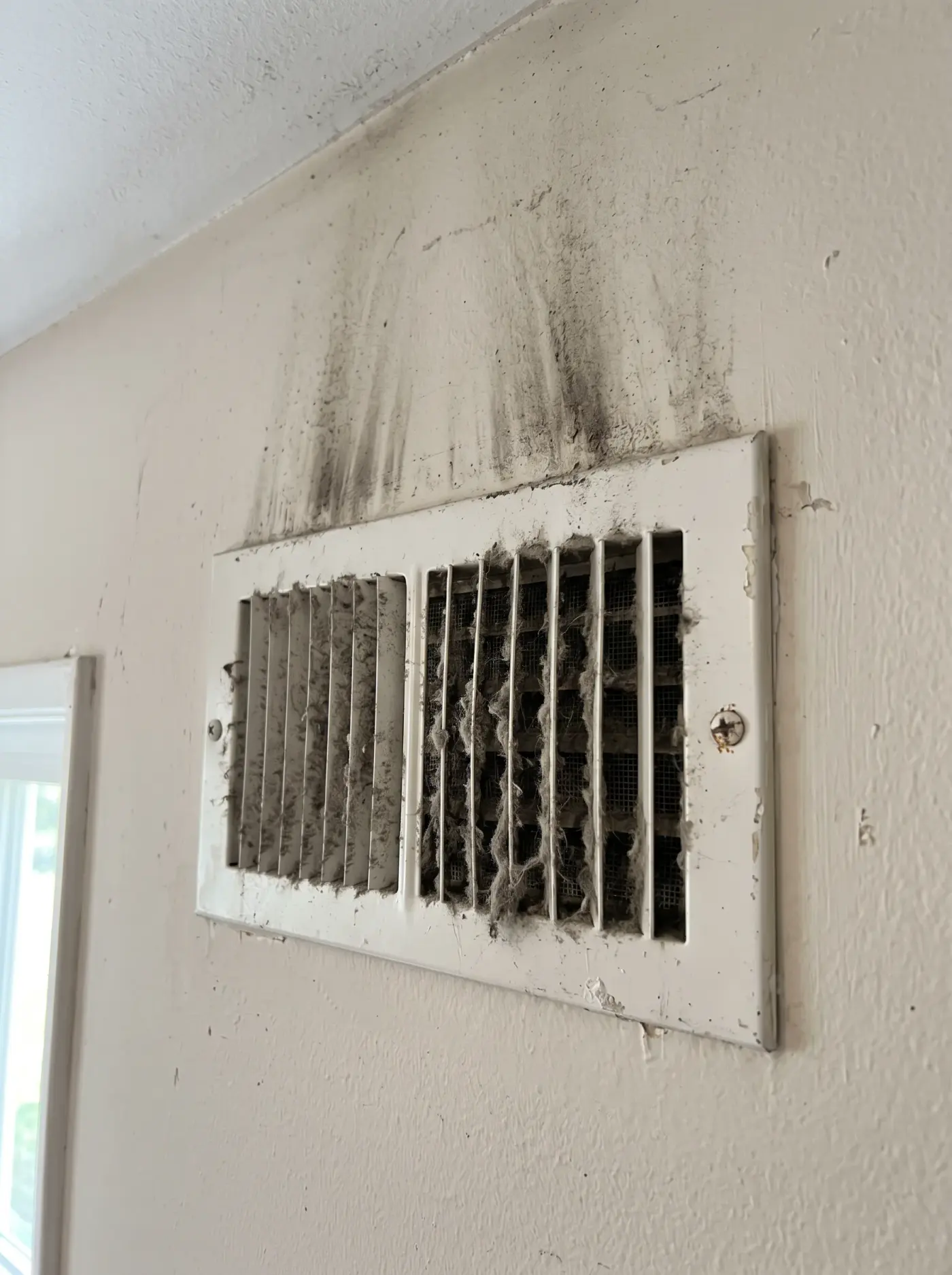 Wall supply register, a dust-caked grille beside the cleared register before cleaning